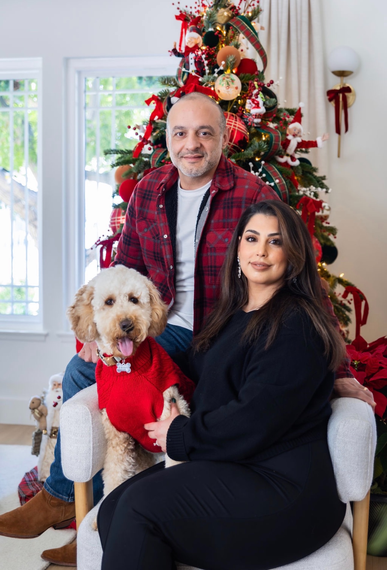 A Kid's Best Doodle family at Christmas holding their cream Goldendoodle in a red sweater at home in California
