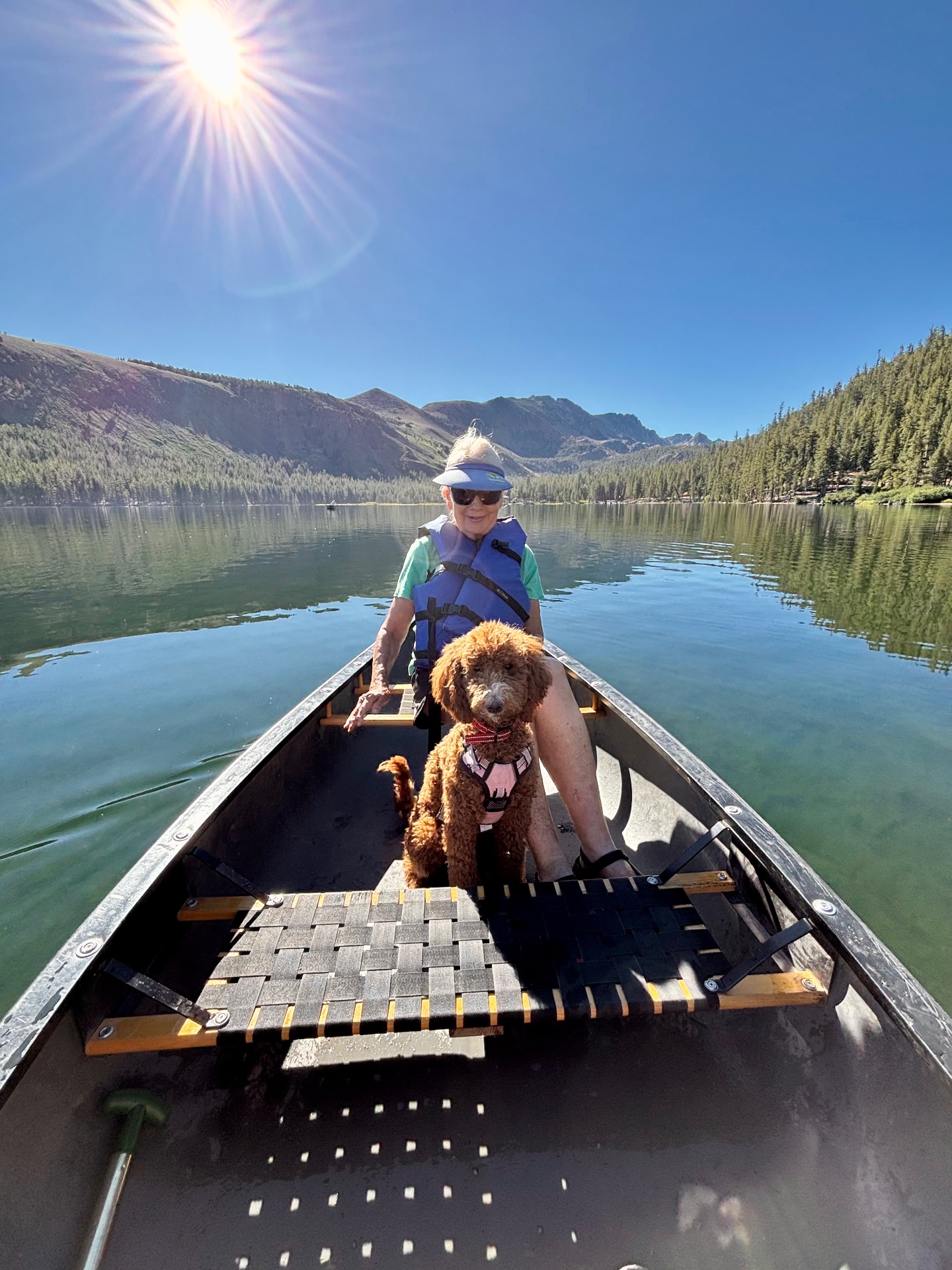 A Kid's Best Doodle owner canoeing on a mountain lake with her red Goldendoodle from Lancaster, California