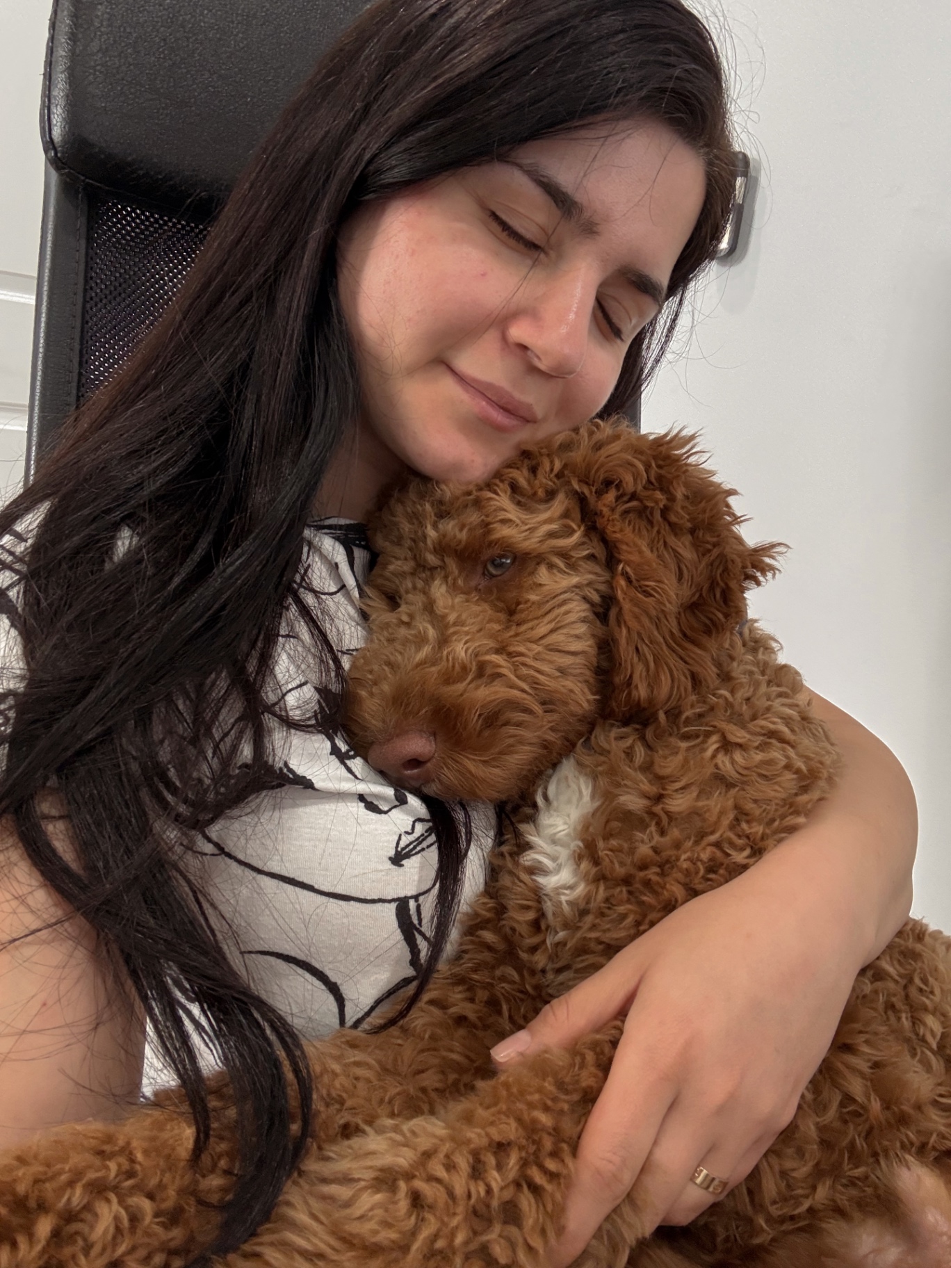 A Kid's Best Doodle owner resting her head against her red Goldendoodle in a quiet, emotional moment at home