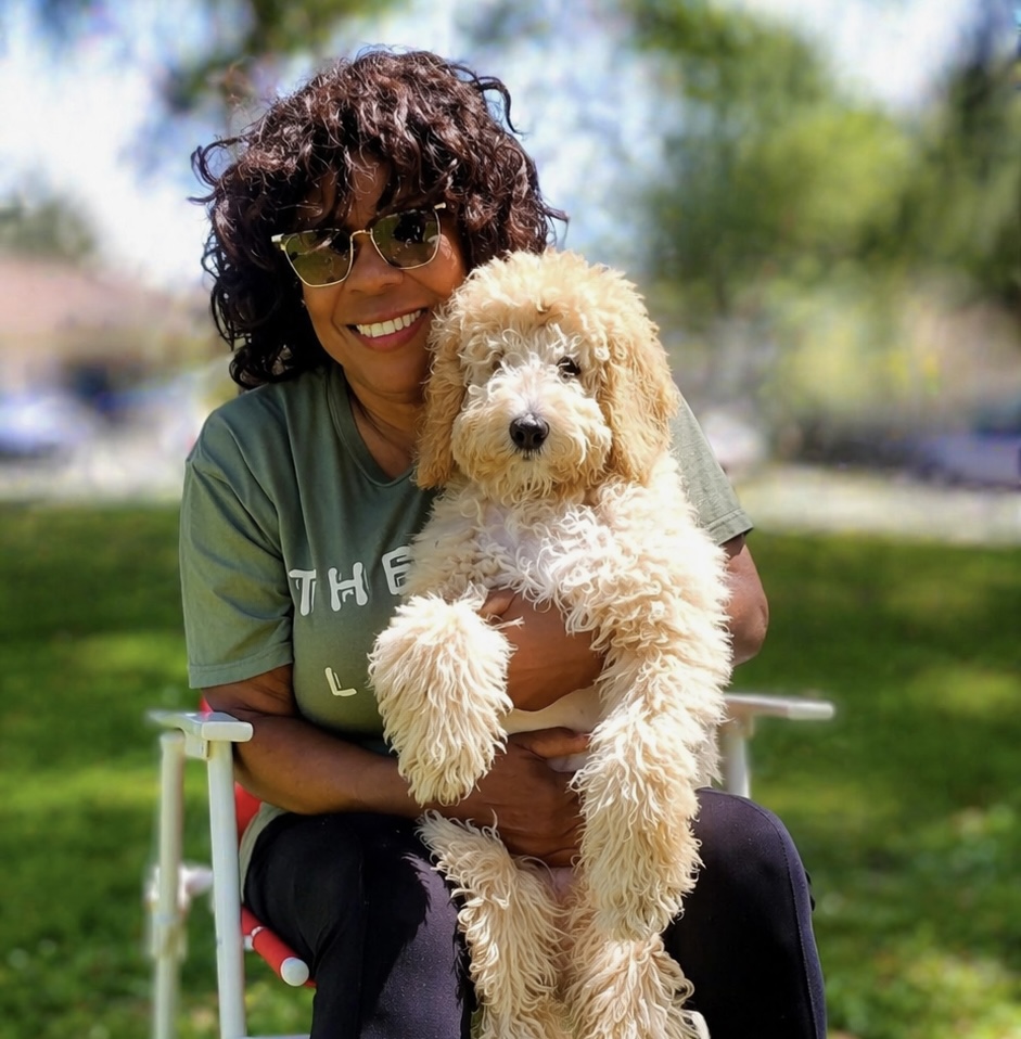 A Kid's Best Doodle family member holding her cream Goldendoodle puppy in the park